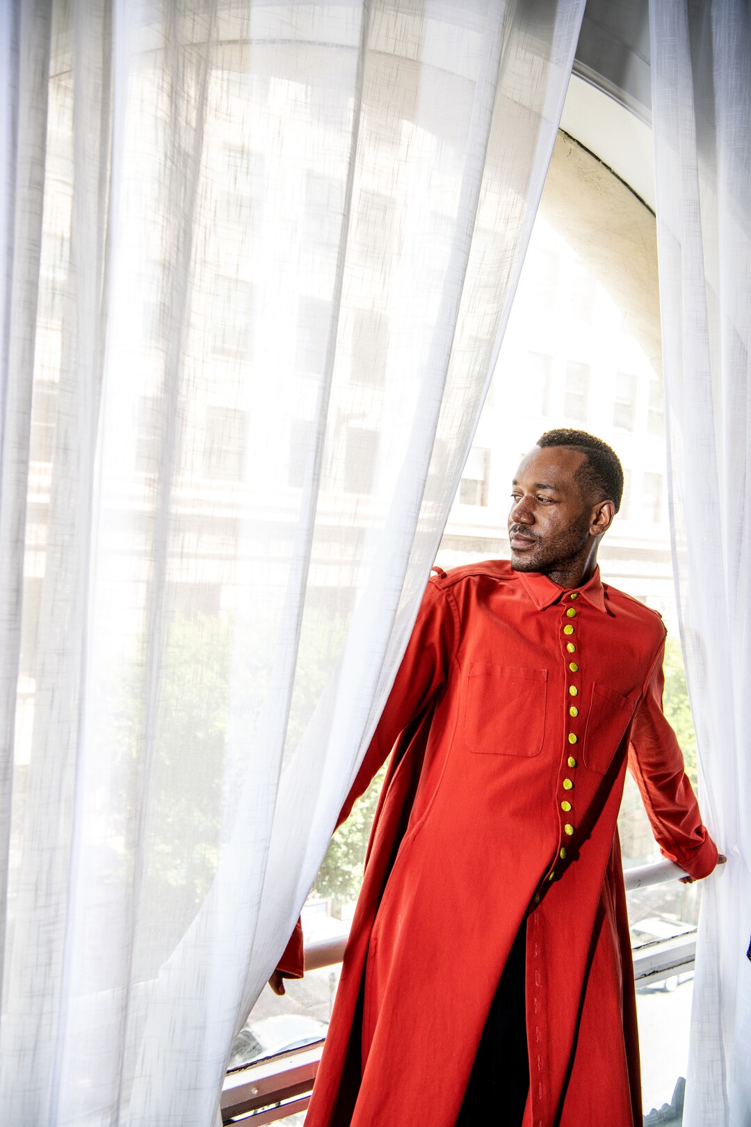 Kenneth Nicholson wears a rust Dorcas Mantle with contrasting velvet buttons paired with black vintage sweatpants.