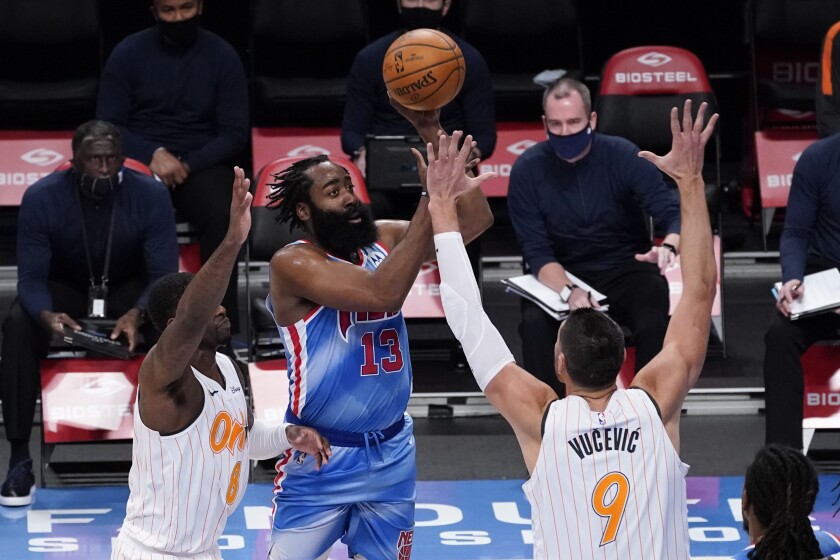 Nets guard James Harden elevates for a shot against Magic forward Dwayne Bacon, left, and center Nikola Vucevic.
