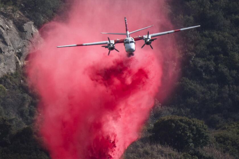 A Cal Fire S2 air tanker makes a fire retardant drop near Top of the World Drive in Laguna Beach. 