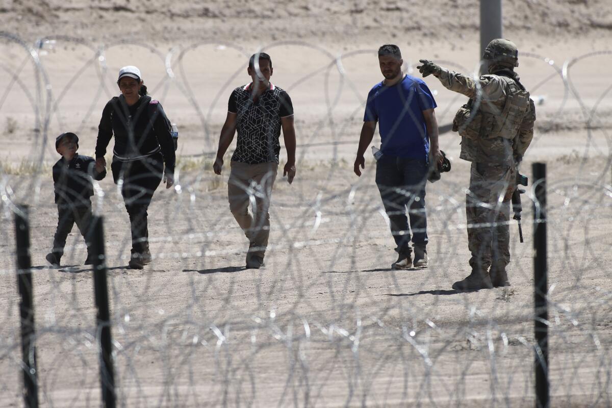 Migrantes esperan a las autoridades estadounidenses en la frontera entre EEUU y México