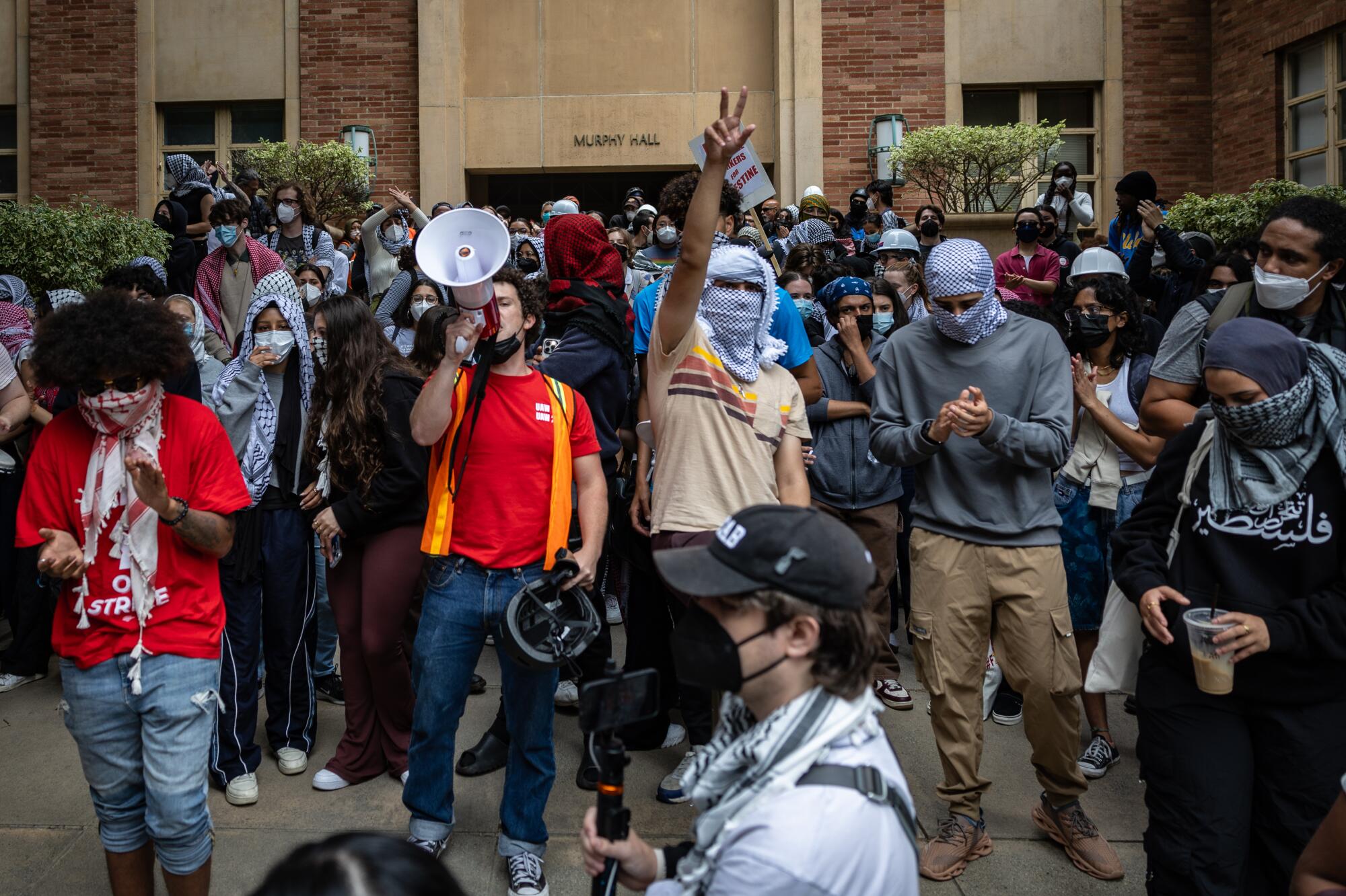 Pro-Palestinian protesters rally, one with a megaphone