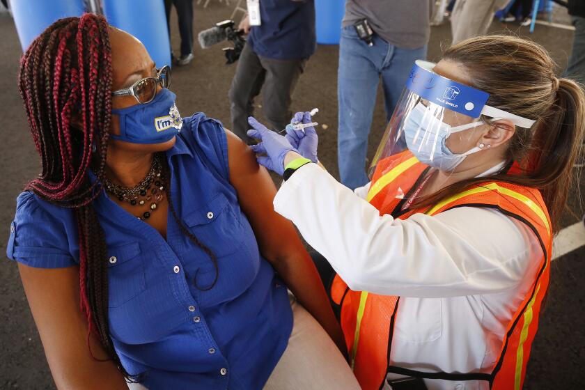 INGLEWOOD, CA - MARCH 01: Letetsia A. Fox, Chapter President Los Angeles 500 of the California School Employees Association receives her first COVID-19 Moderna vaccination shot from registered nurse Sosse Bedrossian, director of nursing services for LAUSD. LAUSD opened the nation's largest vaccination site specifically for education employees at SoFi stadium Monday morning using the Daily Pass, Los Angeles Unified's new technology and data system that coordinates health checks, COVID tests and vaccinations in one simple easy-to-use tool. The site is staffed by Los Angeles Unified school nurses and other licensed healthcare professionals and will have the capacity to administer thousands of vaccines daily for education staff. Anthem Blue Cross is providing volunteer clinical personnel and Cedars-Sinai has provided training to support this vaccination effort. SoFi Stadium on Monday, March 1, 2021 in Inglewood, CA. (Al Seib / Los Angeles Times).