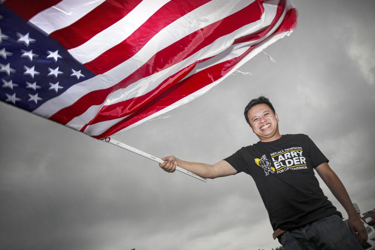 Marc Ang waves an American flag at a recall election rally in Rowland Heights in August. 