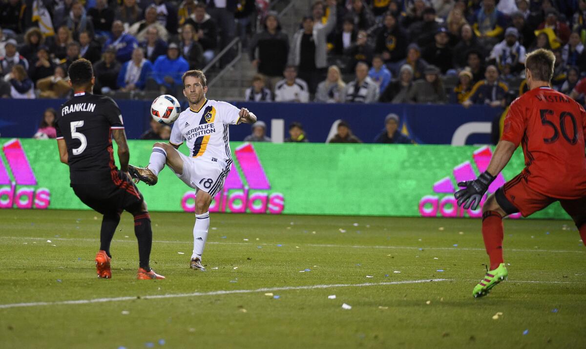 Galaxy forward Mike Magee, center, kicks the ball past D.C. United goalkeeper Andrew Dykstra for a goal as Sean Franklin defends.