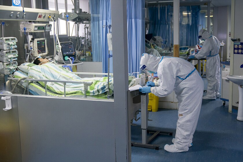 A medical worker tends to a COVID-19 patient in the intensive care unit at Wuhan University's Zhongnan Hospital. 