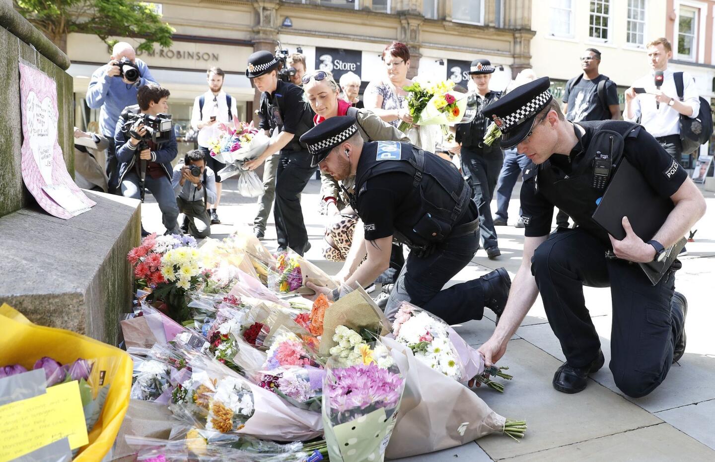 Police officers on May 23, 2017, add to the flowers for the victims of the previous night's explosion at an Ariana Grande concert in Manchester, England.