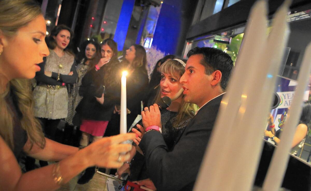 Katrin Malakuti, left, Tabby Davoodi, center, and Sam Yebri get a menorah ready for lighting during 30 Years After's Hanukkah toy drive and mixer.