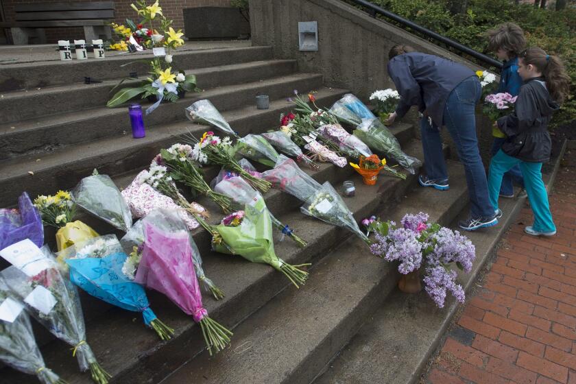 A woman and two children place flowers outside the Codiac Royal Canadian Mounted Police detachment in Moncton.