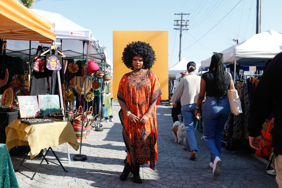 A woman stands outdoors at a flea market. 