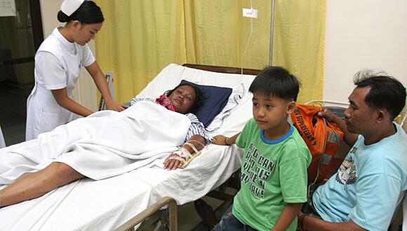 Lita Casumlum recuperates at a hospital in Zamboanga City, Philippines. With her are her husband, Pepito, and 7-year-old son, Christopher.
