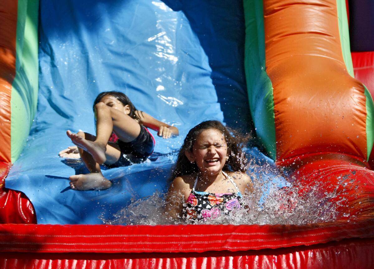 Fourth grader Sophia Martinez splashes into a pool of water after sliding down a water jumper during the Fabulous First Friday at First Lutheran School in Glendale on Friday, Sept. 13, 2013. The event is done on the first full week of school.