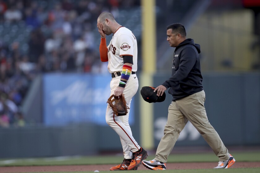 San Francisco Giants third baseman Evan Longoria walks off the field next to head athletic trainer Anthony Reyes after colliding with shortstop Brandon Crawford in the ninth inning of a baseball game against the Chicago Cubs on Saturday, June 5, 2021, in San Francisco. (AP Photo/Scot Tucker)