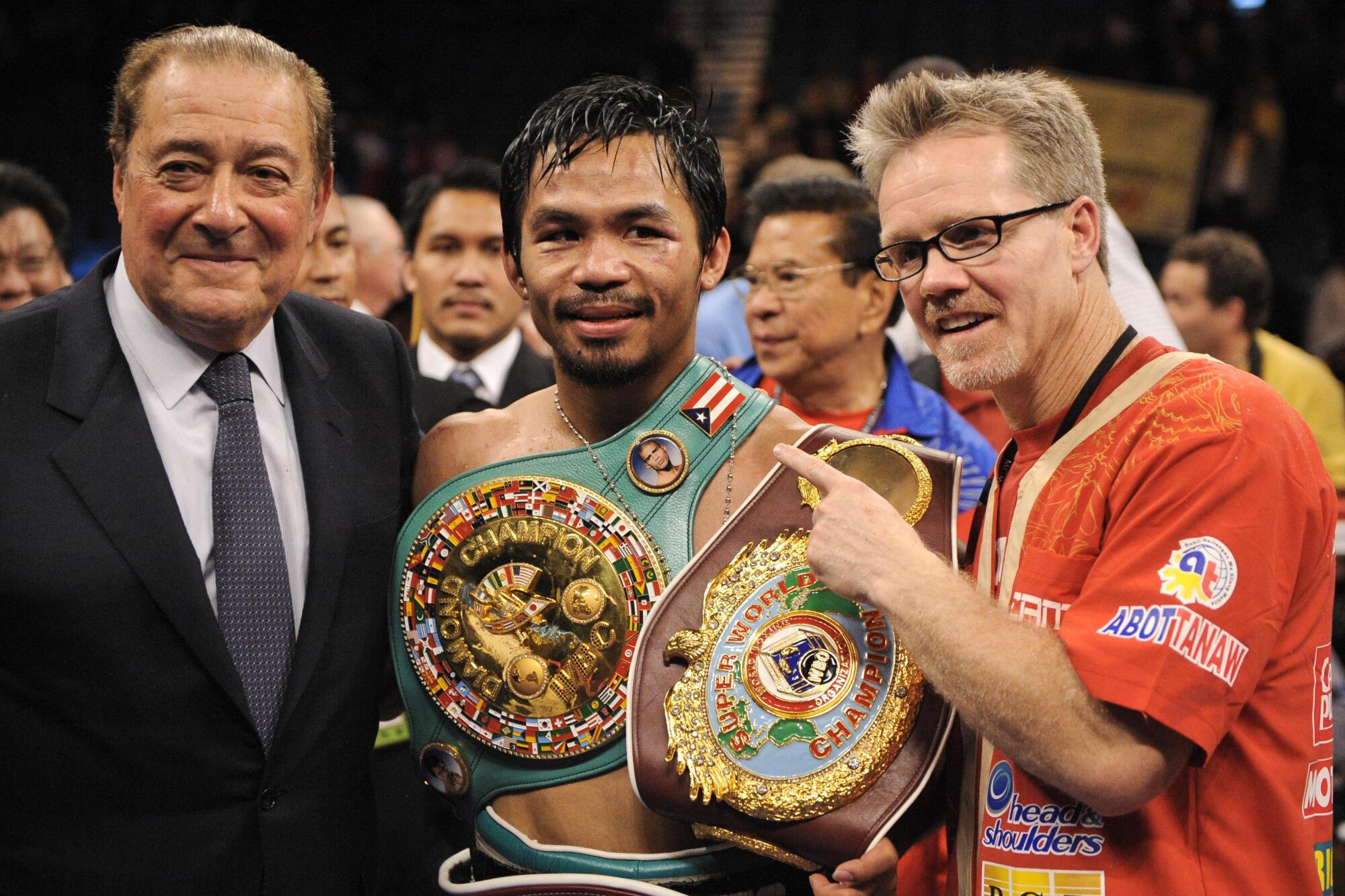 Manny Pacquiao stands between promoter Bob Arum, left, and trainer Freddie Roach after defeating Miguel Cotto in 2009.