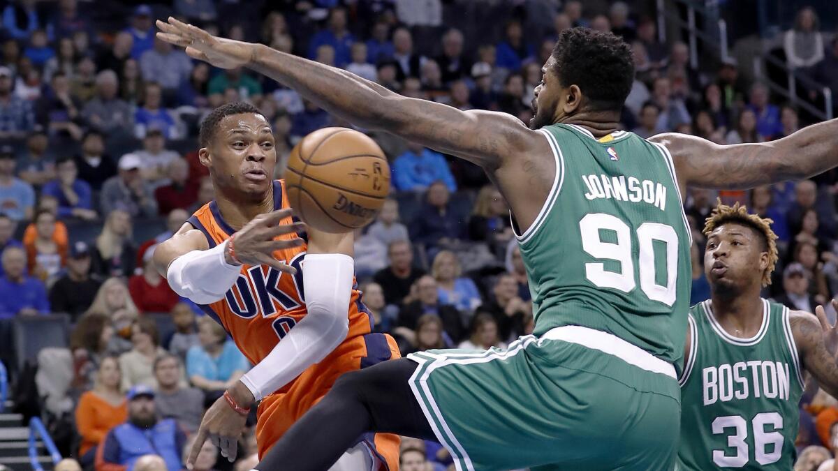 Thunder guard Russell Westbrook (0) passes the ball around Celtics forward Amir Johnson (90) during the first half Sunday.