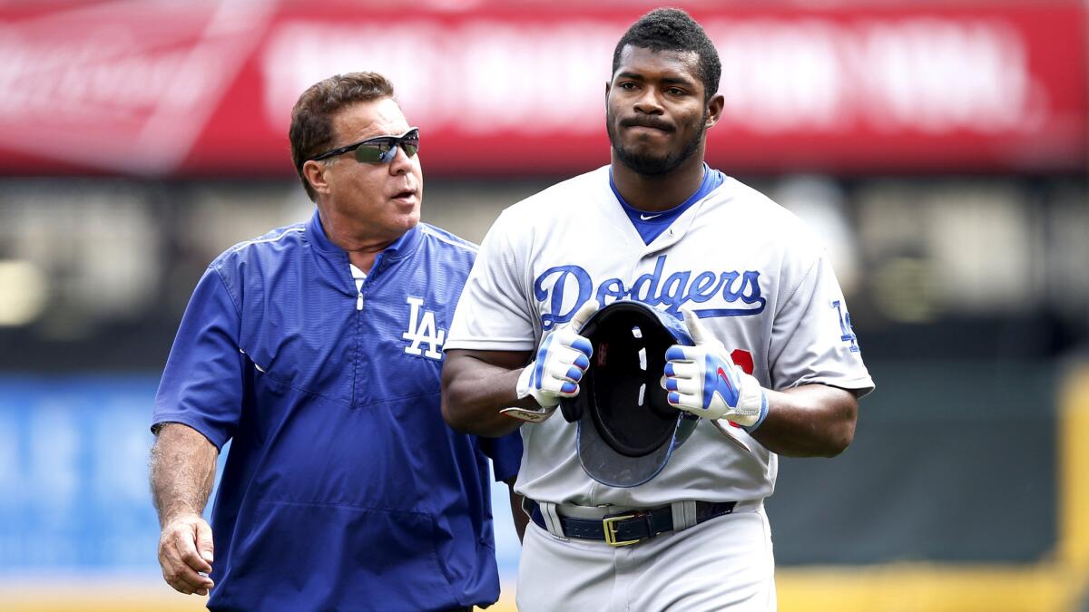 Dodgers right fielder Yasiel Puig leaves the field with trainer Stan Conte after injuring his right hamstring while running to first base on Aug. 27 in Cincinnati.