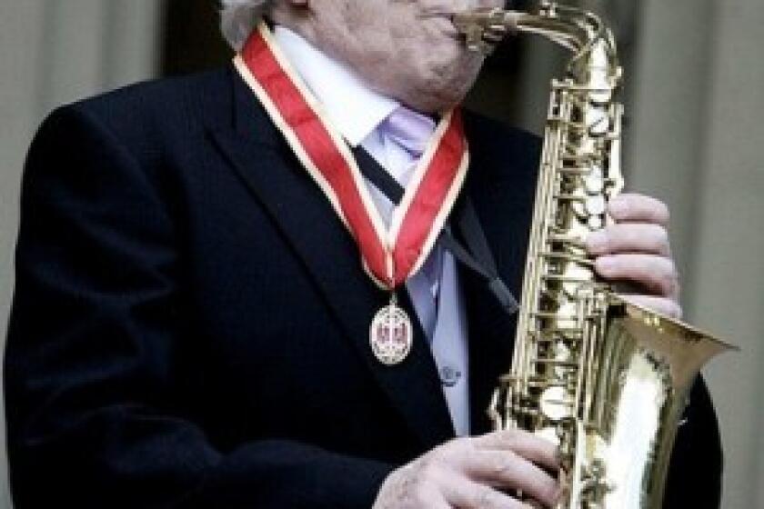 John Dankworth plays his saxophone at Buckingham Palace in 2006 after receiving a knighthood from Queen Elizabeth II.