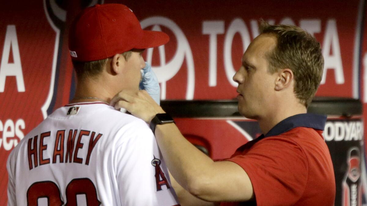 Angels trainer Adam Nevala tends to the bloody nose of pitcher Andrew Heaney in the middle of the second inning during a game April 5.