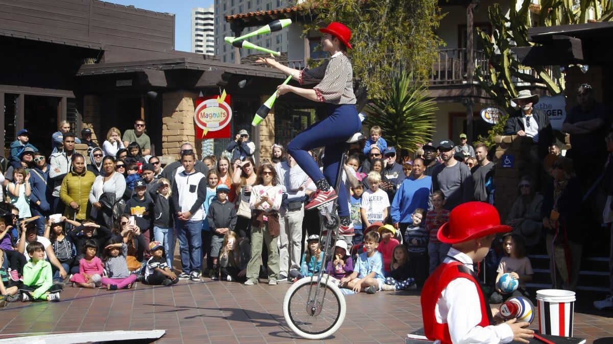 Ananda Reilly with the Circus Mafia from San Diego performs on a unicycle while juggling for the crowd at Seaport Village Spring Festival.