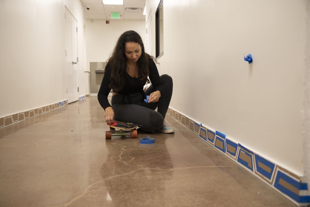 Jessica Petrikowski paints the baseboards of the Chicano Park Museum and Cultural Center ahead of its grand opening.