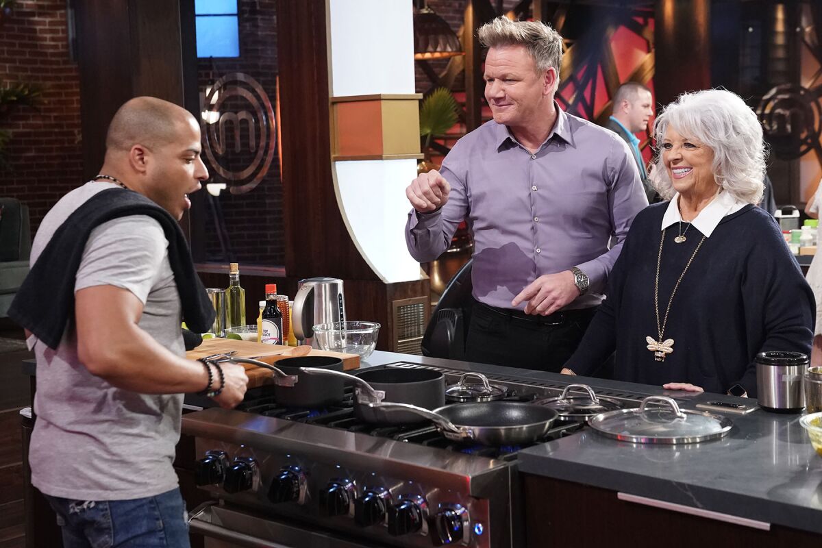 A contestant, left, cooks for Gordon Ramsay and Paula Dean on "MasterChef."