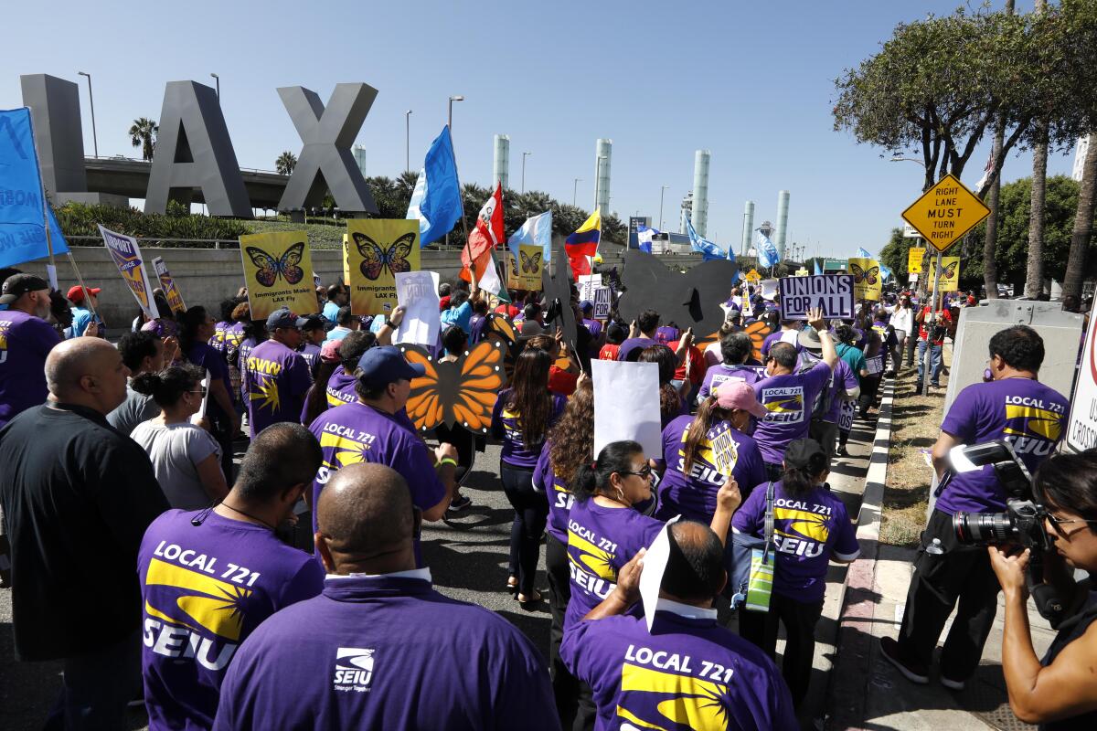 Hundreds of people in march outside LAX in purple union shirts.