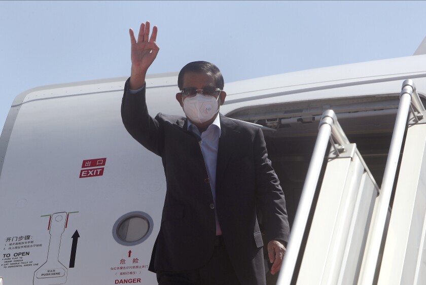 Cambodian Prime Minister Hun Sen waves from a plane upon his arrival from Myanmar, at Phnom Penh International Airport, in Phnom Penh, Cambodia, Saturday, Jan. 8, 2022. Prime Minister Hun Sen's visit to Myanmar seeking to revive peace efforts after last year's military takeover has provoked an angry backlash among critics, who say he is legitimizing the army's seizure of power. (AP Photo/Heng Sinith)