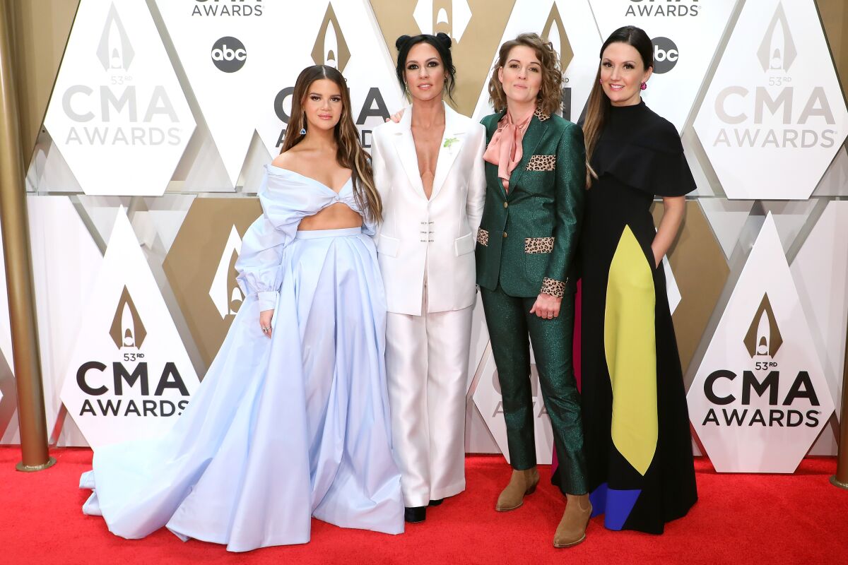 Four women in a country music band walk the red carpet at an awards show.