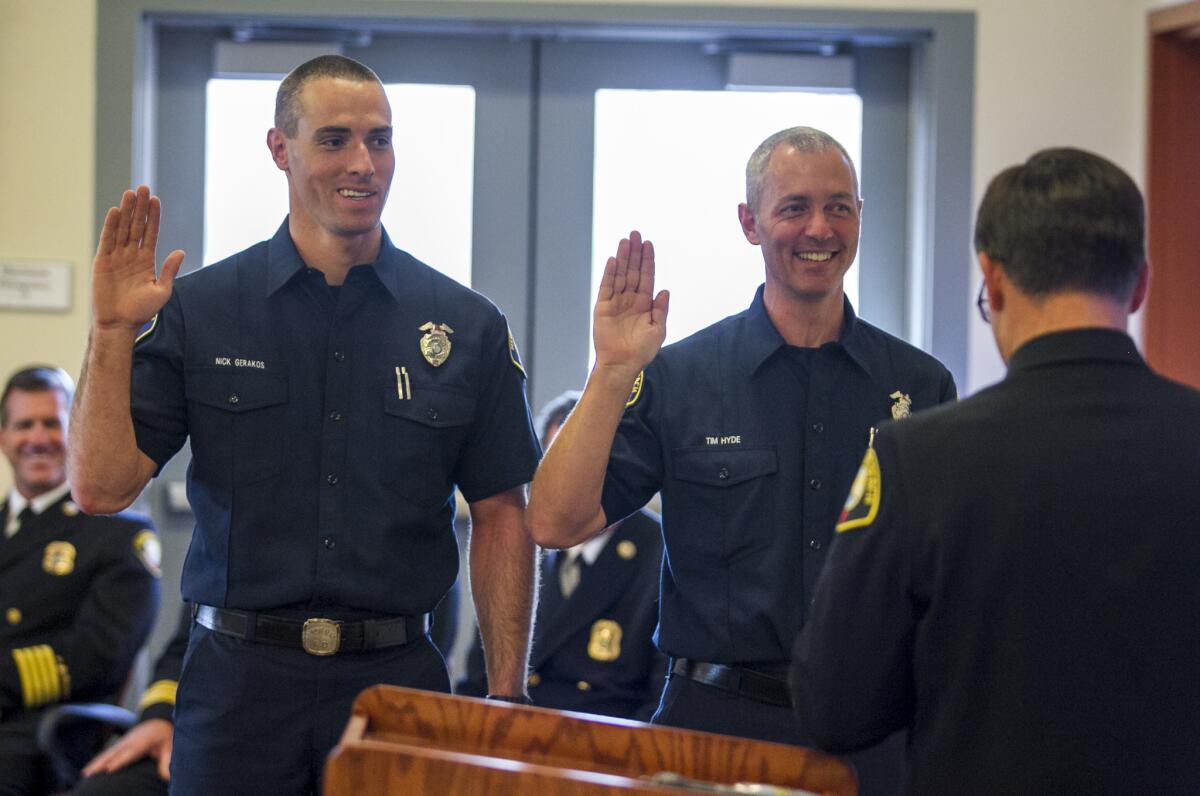 Assistant Chief Chip Duncan, right, swears in probationary firefighters Nick Gerakos, left, and Tim Hyde at fire station 7 on Friday.