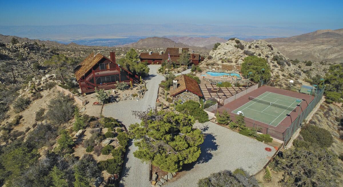 Frank Sinatra's desert hideaway from a bird's eye view shows hills, greenery, buildings, driveway, a tennis court and a pool.