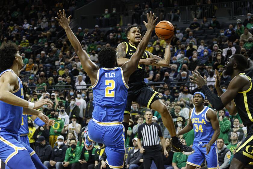 Oregon guard Jacob Young, center right, shoots against UCLA forward Cody Riley (2) in the first half of an NCAA college basketball game in Eugene, Ore., Thursday, Feb. 24, 2022. (AP Photo/Thomas Boyd)