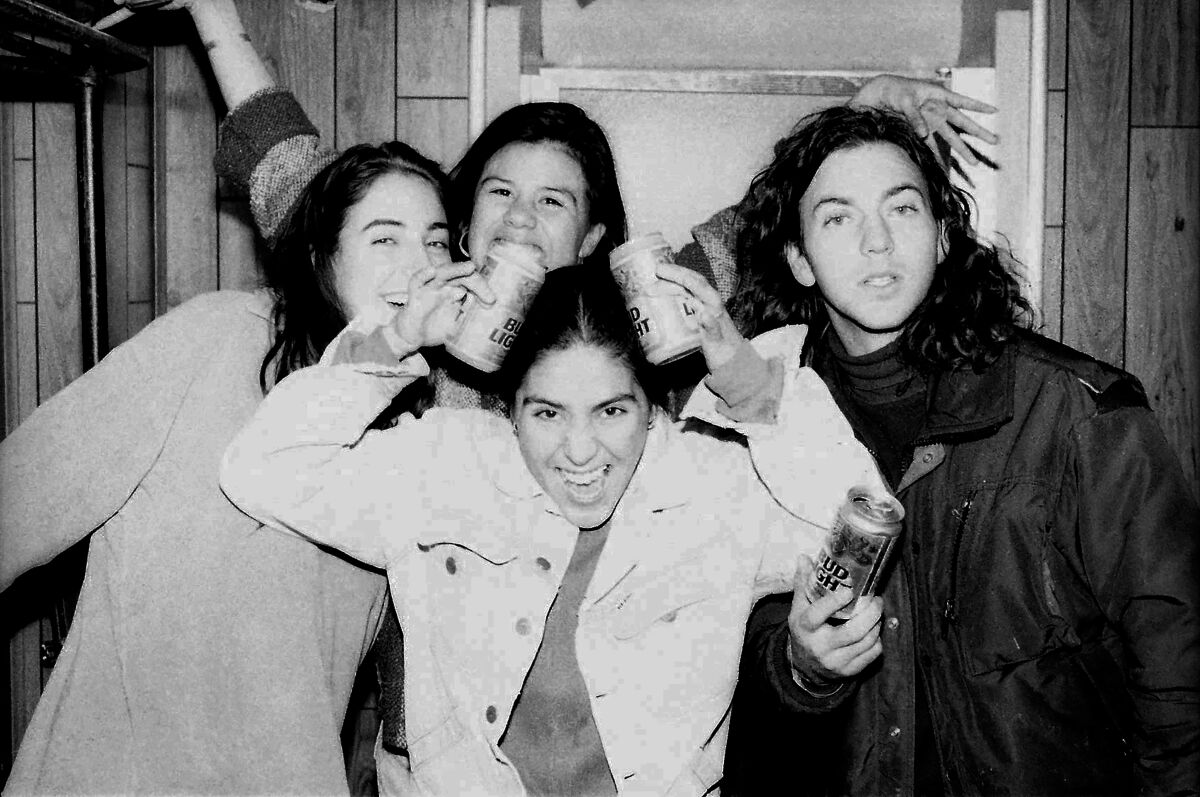 Three women and a man pose for a photo backstage at a rock concert