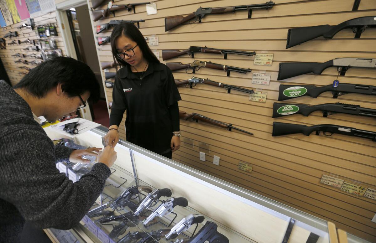 Queenie Yang, center, an employee of Gun Effects Guns & Ammo, helps customer Felix Gao with his firearm safety certification paperwork. Gun Effects was started by a Chinese immigrant three years ago in Southern California, and its clientele is nearly half Chinese immigrants.
