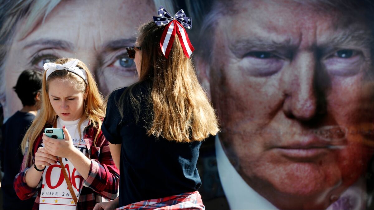 People pause near a bus adorned with large photos of candidates Hillary Clinton and Donald Trump before the presidential debate at Hofstra University in Hempstead on Monday.