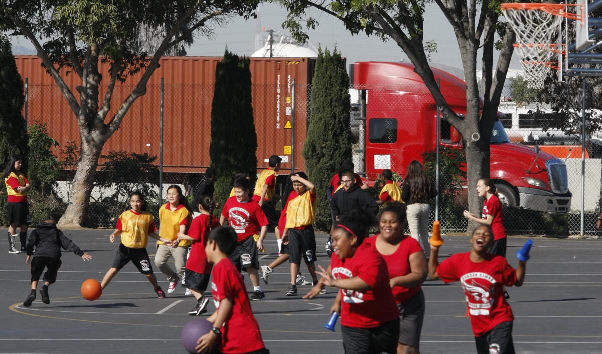 Children born and raised near inner-city pollution sources can wind up with reduced white matter in their brains and greater developmental and behavioral problems, a study suggests. Above, a Long Beach school near an oil refinery, freeway, railroad line and seaport.