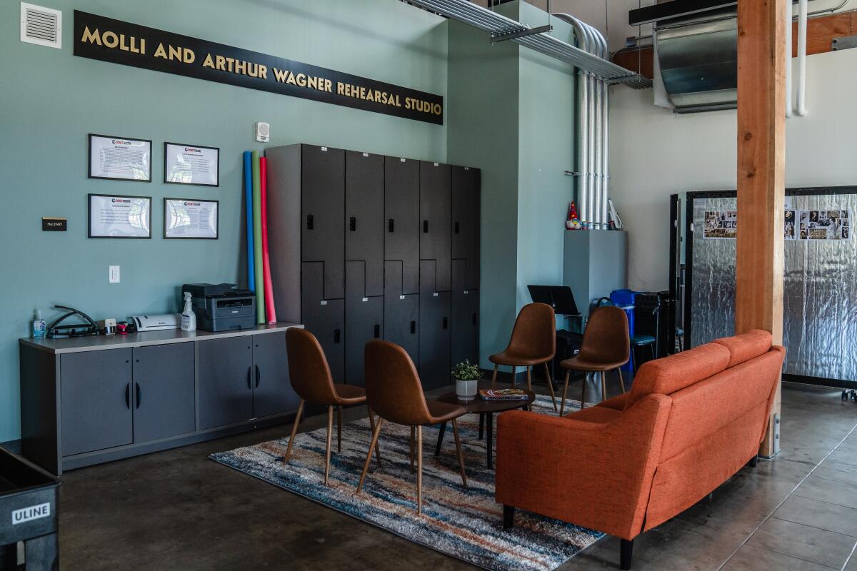 A room with lockers, chairs, a coffee table, rug and a couch.