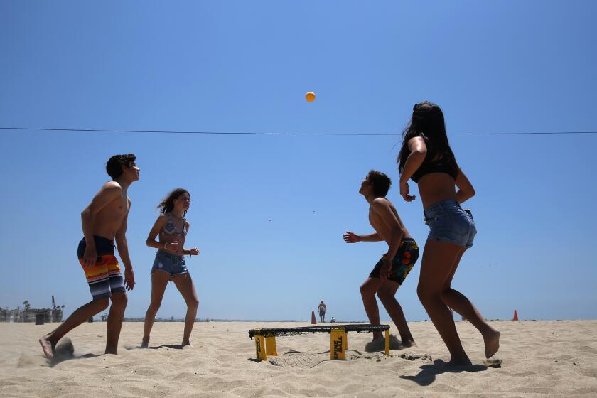 ORANGE COUNTY, CA - MAY 11: Shawn Jones, Yari Perkins, Kalani Delarole and Keira Toor, left to right, play spikeball at Seal Beach on Monday, May 11, 2020 in Orange County, CA. Seal Beach reopened to active use on Monday and will only be open during daylight hours Monday through Thursday. (Dania Maxwell / Los Angeles Times)