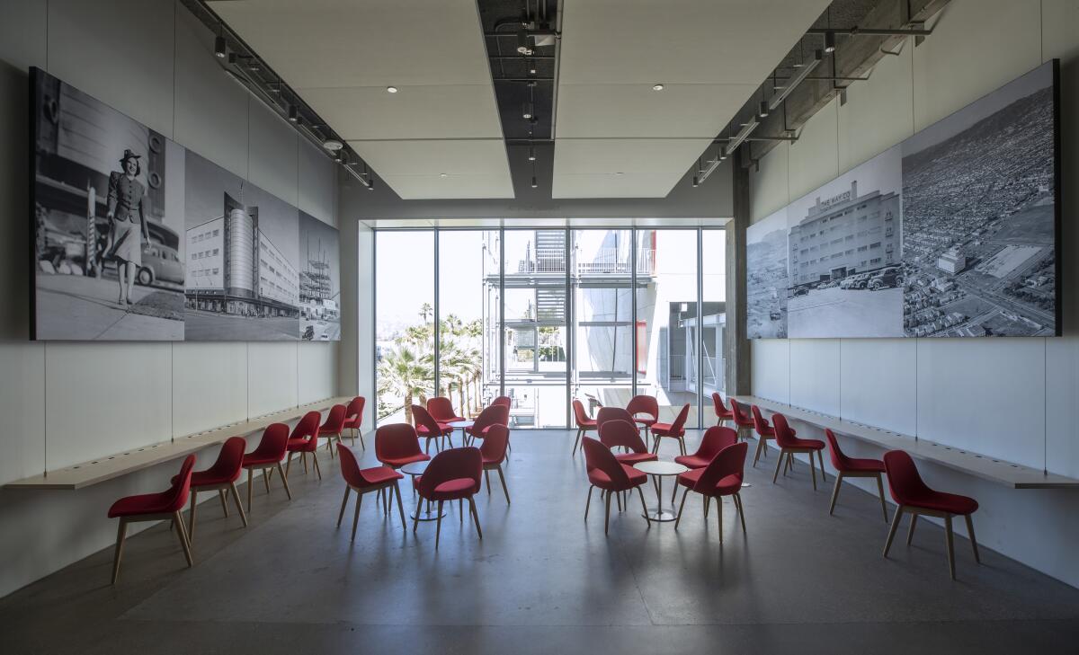 A lounge with red chairs is lined with vintage photos of the area around Wilshire and Fairfax.