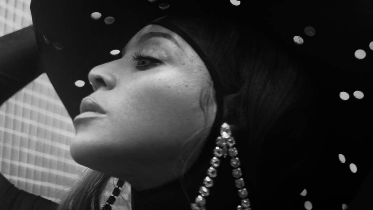 A black and white close-up of a woman wearing a large, dangly earring and hat