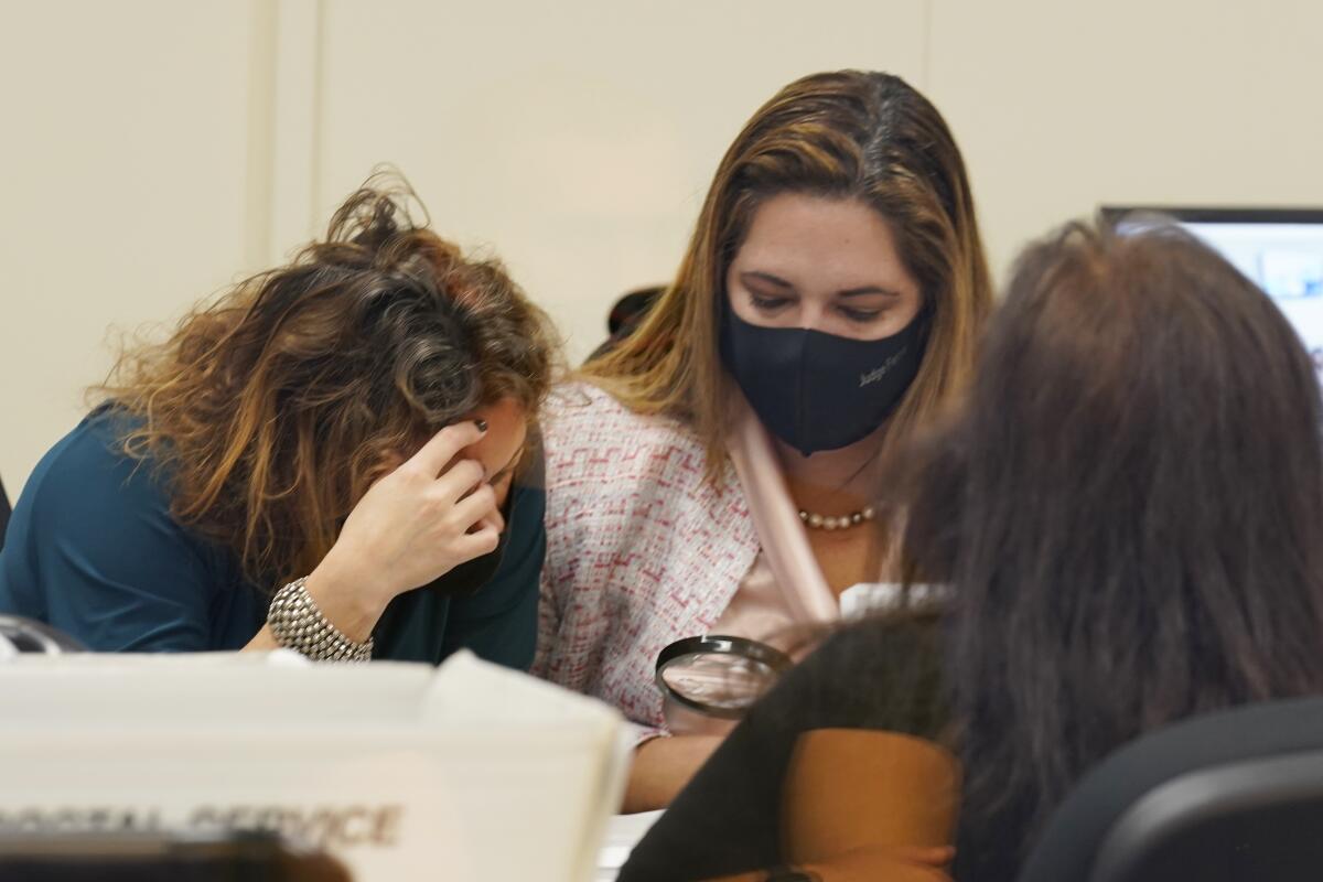 Judges Milena Abreu, left, and Victoria Ferrer examine a vote-by-mail ballot.