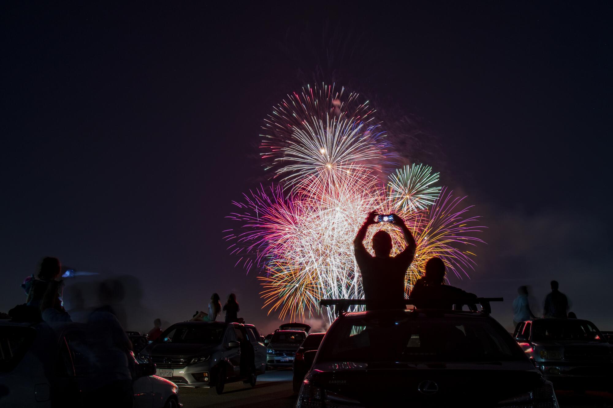 Spectators sit on the roofs of their vehicles to watch the fireworks during the Drive-Up 4th of July Spectacular