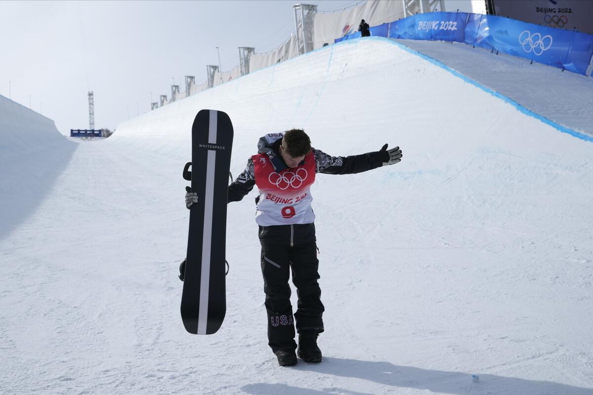 Shaun White holds his snowboard and bows at the 2022 Olympics.