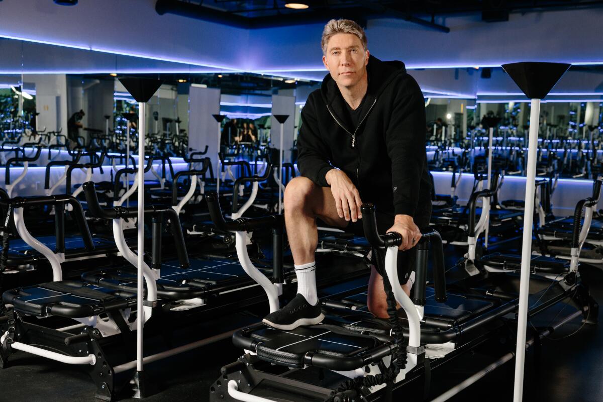 A man poses for a photo while kneeling on an exercise machine