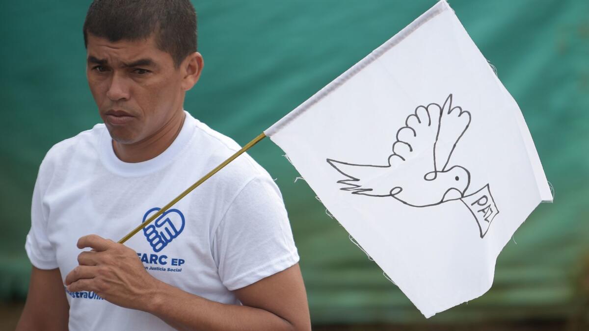 A FARC rebel carries a flag with the word "peace."