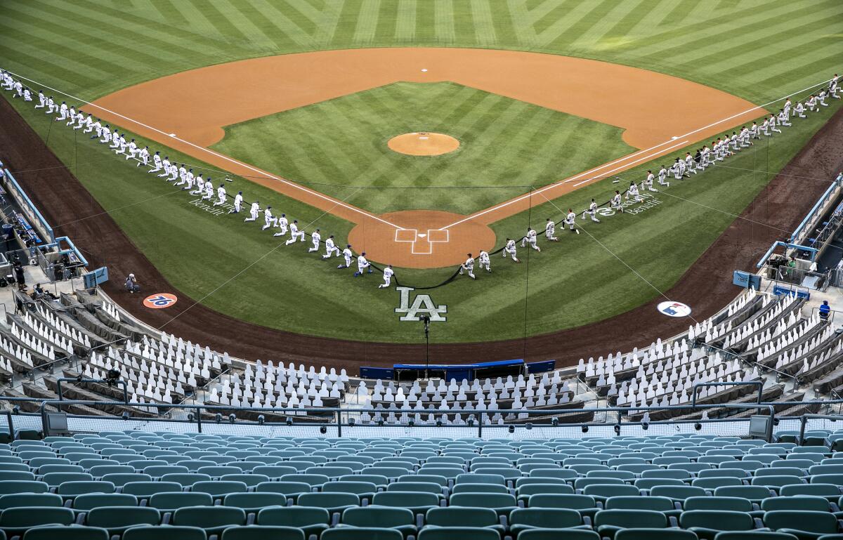 Aerial view of baseball players kneeling along the base paths while holding a long black ribbon in an empty stadium