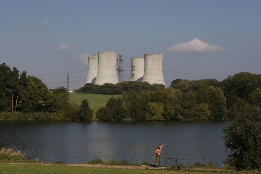 FILE - a man fishes with the towering Dukovany nuclear power plant in the background, in Dukovany, Czech Republic, Sept.. 27, 2011. The Czech Republic’s major power company signed a deal on Wednesday, March 29, 2023 with U.S. Westinghouse Electric Co. to deliver fuel supplies for the Dukovany nuclear plant, erasing the country’s dependence on Russia. (AP Photo/Petr David Josek, File)