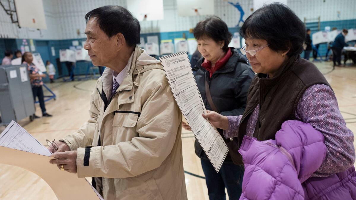 Zhou Nan Zhou, left, his wife, Li Li Tan, and their friend, Yulsman Yang -- all originally from China -- wait to cast their ballots Tuesday in New York City.