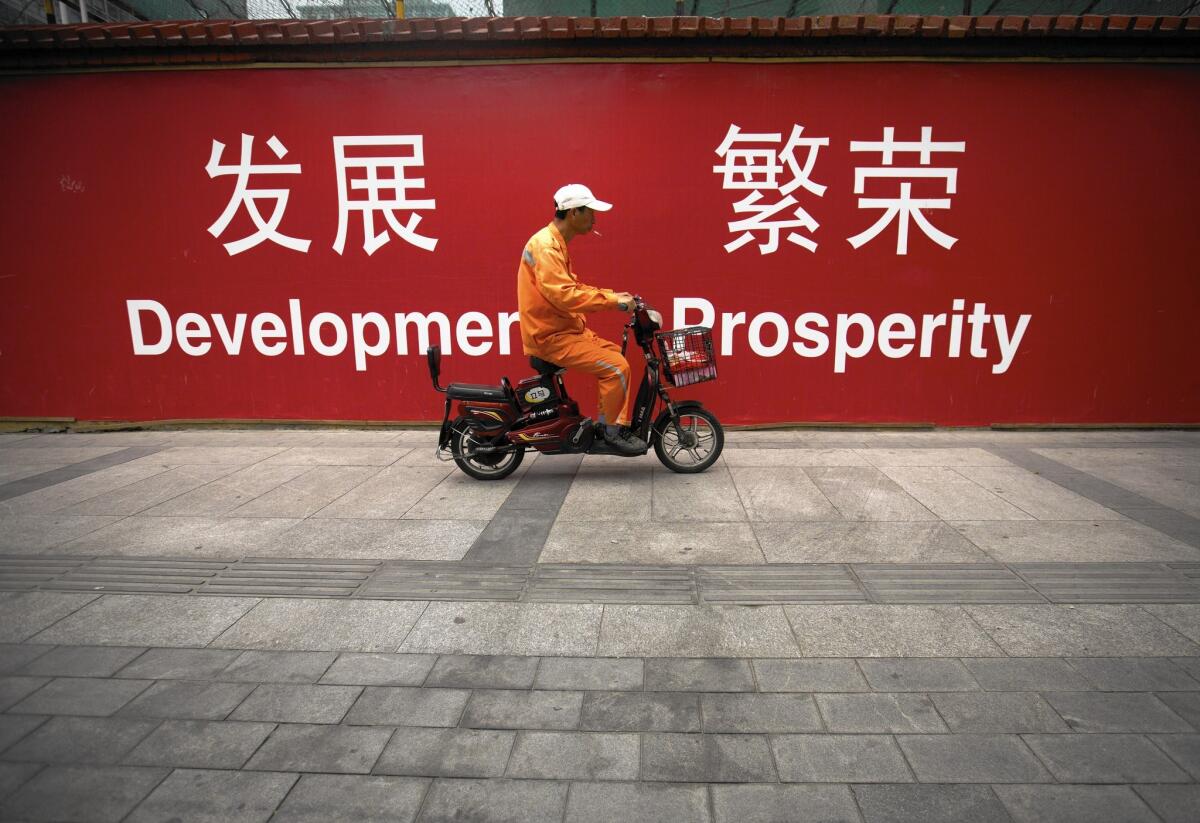 China's total debt has nearly quadrupled since 2007, to more than $28.2 trillion, according to the McKinsey Global Institute. Above, a maintenance worker rides a scooter past banners reading "Development" and "Prosperity" in English and Chinese on a Beijing street.