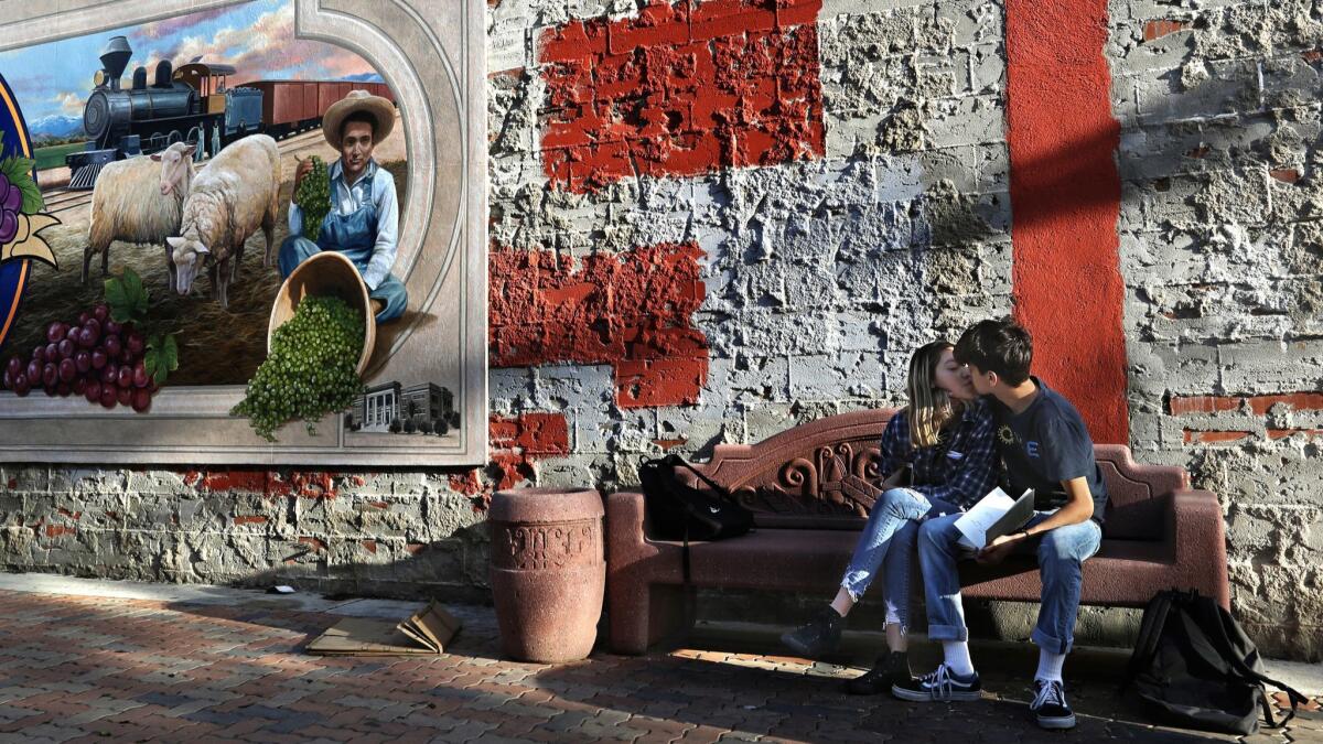 Natalie Lopez and Eduardo Fernandez, students at Delano High School, spend time together after class next to a mural celebrating the town's 100th anniversary, which took place in 2015.