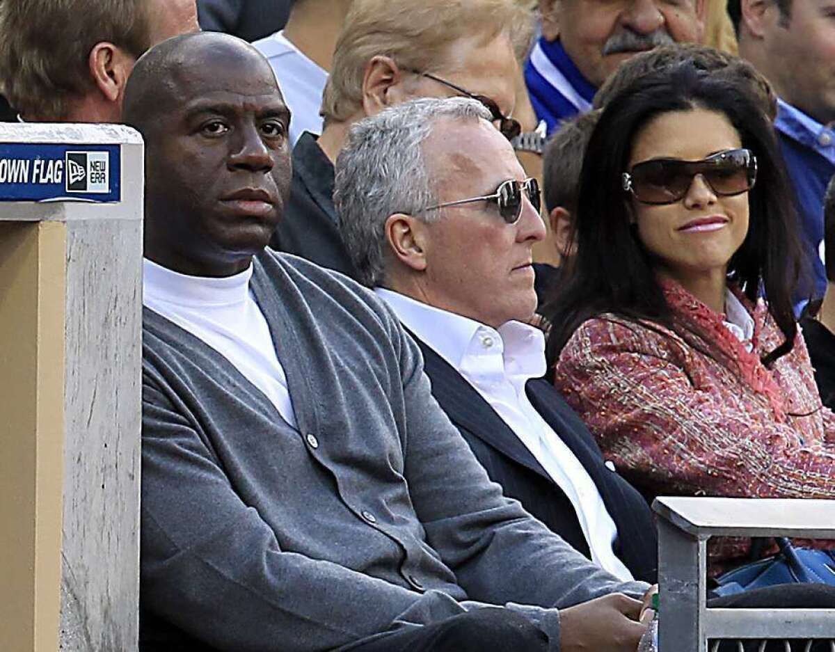 Magic Johnson, left, and Frank McCourt watch the Dodgers play on April 5, 2012.