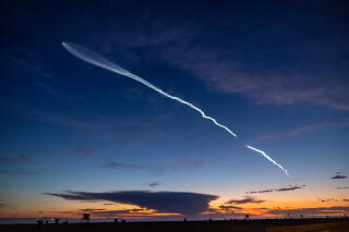 A sunset with a white streak in the sky.